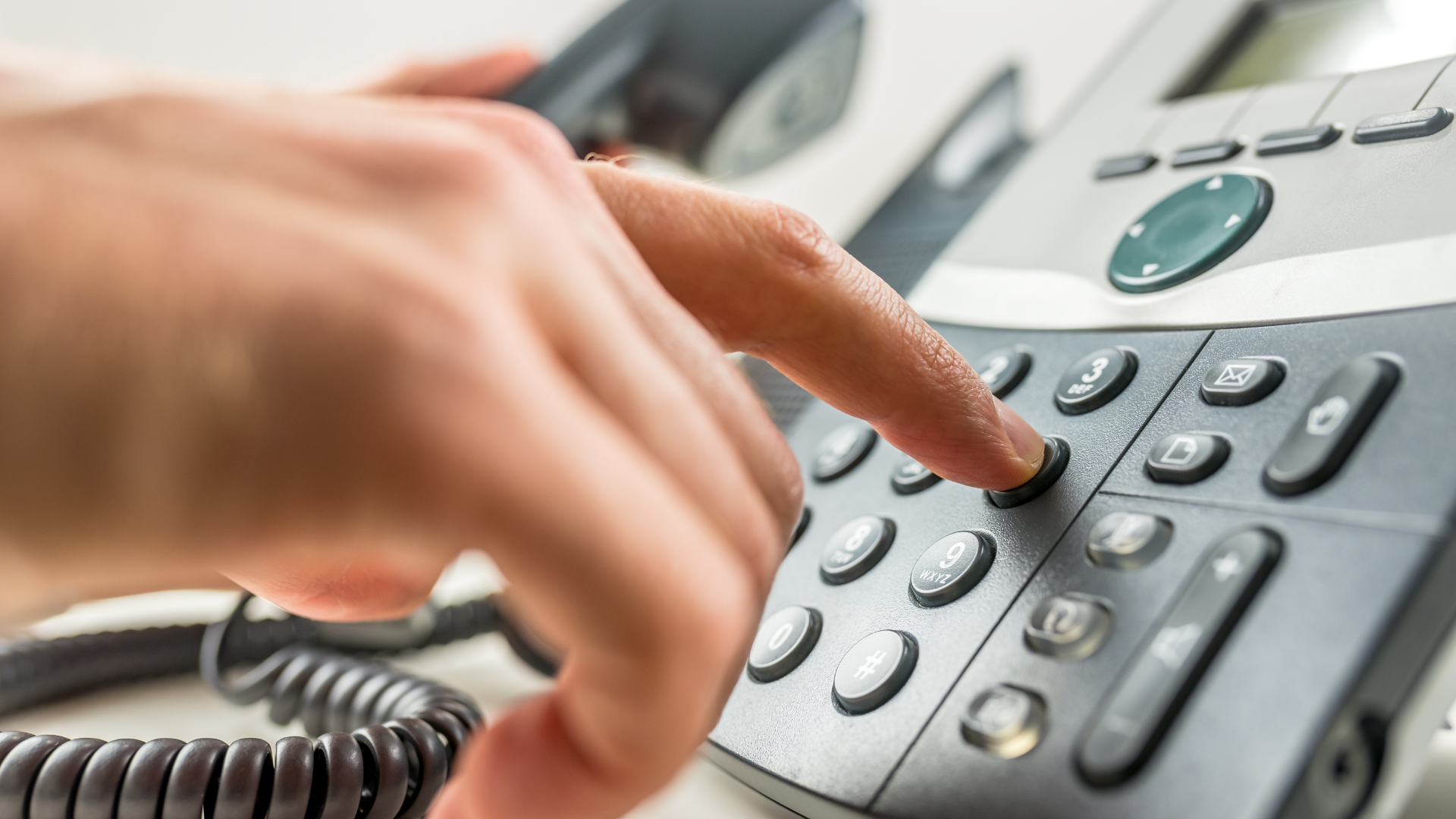 Image d'une personne qui tape un numéro sur un téléphone fixe